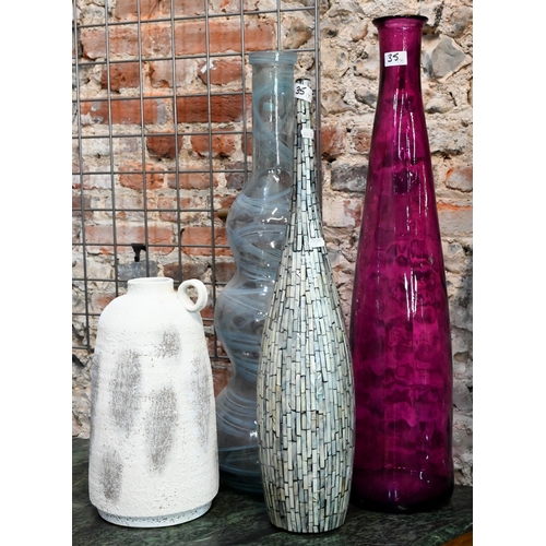 35 - A red glass carboy of cylindrical form, a green glass carboy, two tall glass vases, a ceramic vase w... 