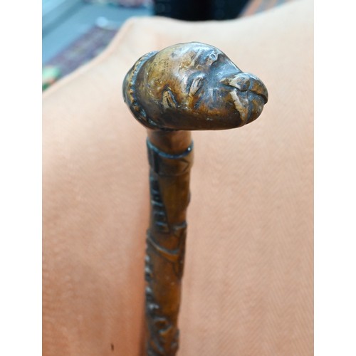 413 - An antique Welsh walking stick, the handle as a dogs head and radially carved in relief 'Whose Matth... 