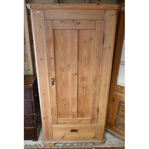 175 - A pine single wardrobe with panelled door enclosing brass rail over the single drawer, 92 cm w x 46 ... 