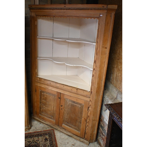 176 - An antique pine corner cabinet with cream painted open shelves over panelled cupboard doors, 130 cm ... 