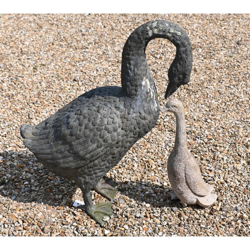 202 - A green bronze patinated garden geese sculpture to/w a small cast stone goose, 58 cm high, a/f (2)