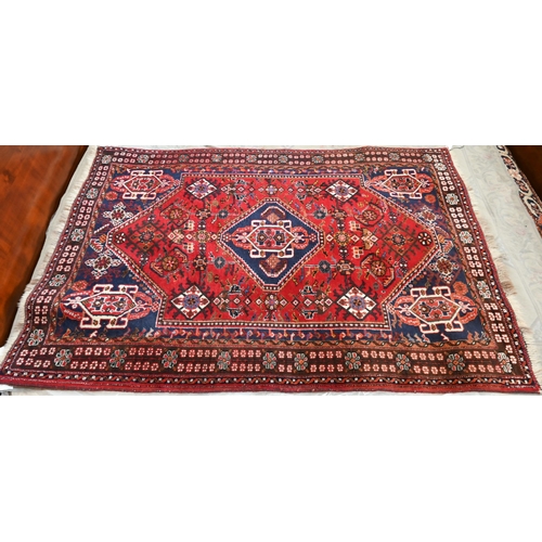 514 - A Persian Shiraz rug with central blue medallion on red ground within floral brown border to/w a Per... 