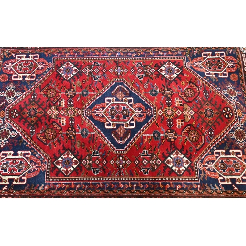 514 - A Persian Shiraz rug with central blue medallion on red ground within floral brown border to/w a Per... 