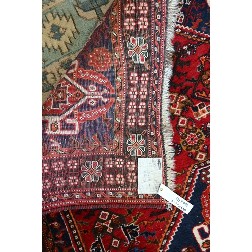 514 - A Persian Shiraz rug with central blue medallion on red ground within floral brown border to/w a Per... 