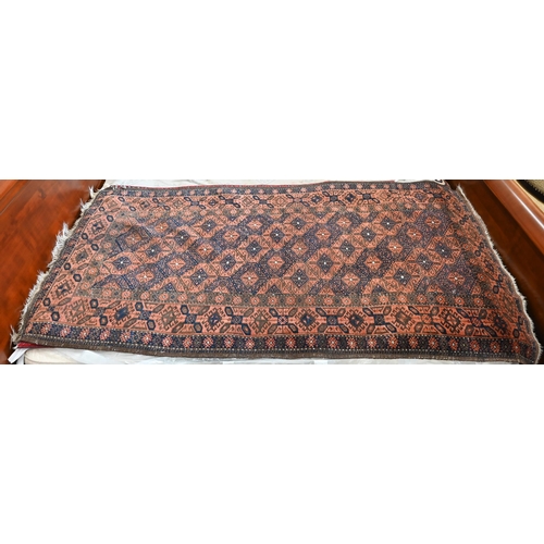 515 - A Persian Baluchi brown ground rug with repeating diamond design, 206 cm x 113 cm