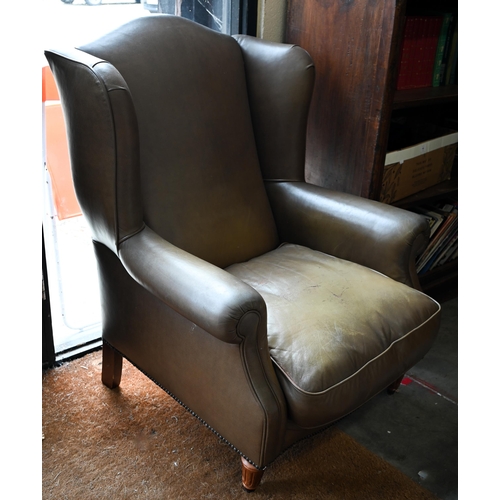 58 - A Georgian style leather wingback armchair with turned front legs and brass castors (loose)