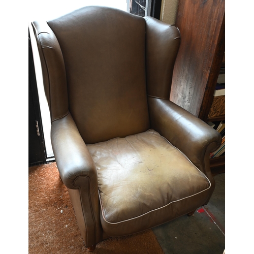 58 - A Georgian style leather wingback armchair with turned front legs and brass castors (loose)