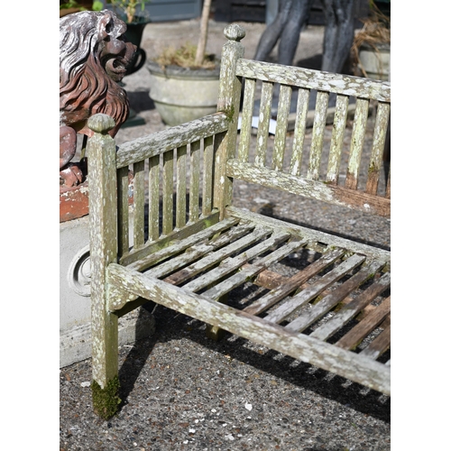 6 - A scarce Edwardian, Heals of London teak two seater garden bench, with moulded post finials, one sea... 