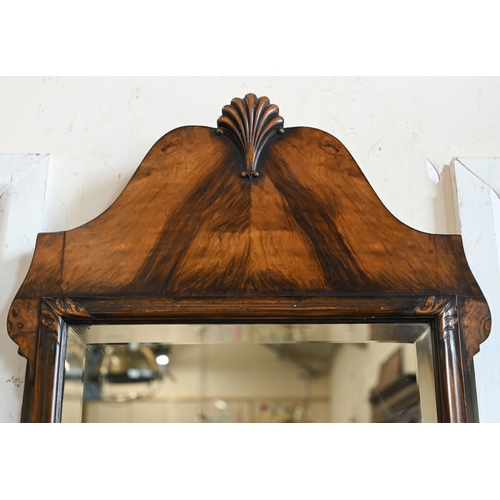 62 - An Edwardian walnut framed mirror with shell carved crest and bevelled plate, 36 x 74 cm