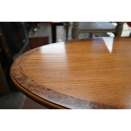 75 - Modern golden oak and burr walnut banded oval coffee table with four turned pillars and quadraform b... 