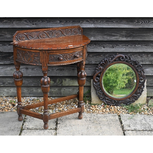 134 - A carved oak demi-lune side table, 77 cm w x 76 cm h to/w a circular oak fret-cut wall mirror, 56 cm... 