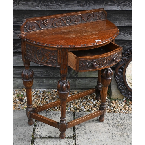 134 - A carved oak demi-lune side table, 77 cm w x 76 cm h to/w a circular oak fret-cut wall mirror, 56 cm... 