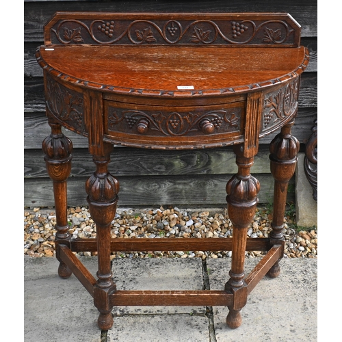 134 - A carved oak demi-lune side table, 77 cm w x 76 cm h to/w a circular oak fret-cut wall mirror, 56 cm... 