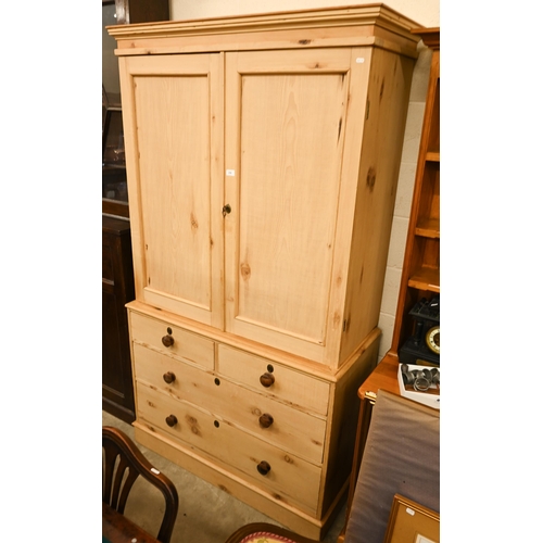 A stripped pine linen press with twin panelled doors enclosing sliding shelves, above two short and two long drawers, 115 x 51 x 207 cm h