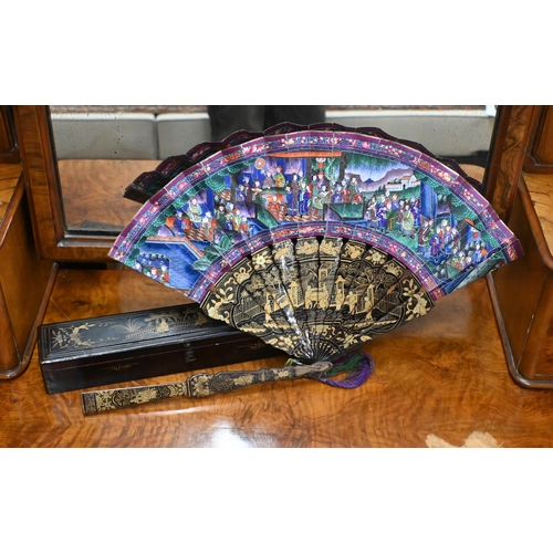 457 - An antique Cantonese fan with gilded black lacquer sticks and painted paper leaf decorated on both s... 