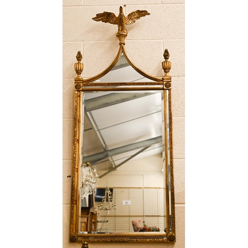 56 - A gilt framed wall mirror surmounted by a spread eagle flanked by urns, 124 x 51 cm