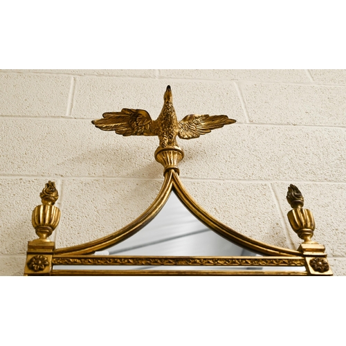 56 - A gilt framed wall mirror surmounted by a spread eagle flanked by urns, 124 x 51 cm