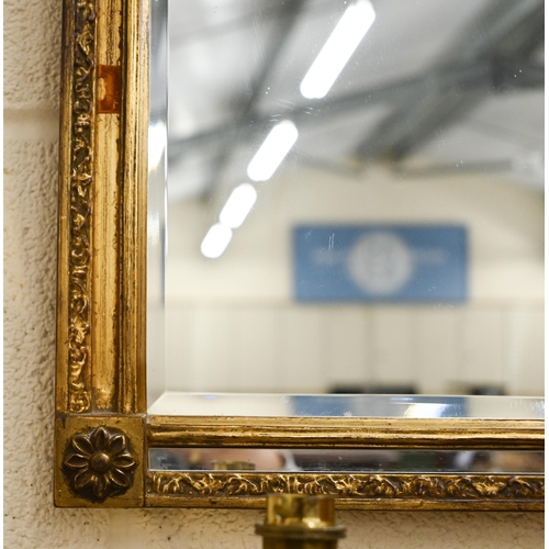 56 - A gilt framed wall mirror surmounted by a spread eagle flanked by urns, 124 x 51 cm