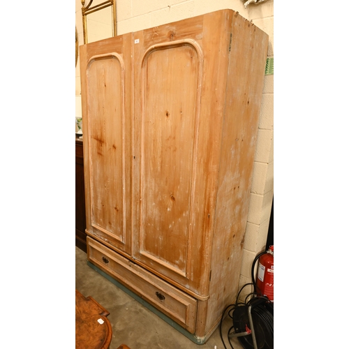 58 - A Victorian stripped pine wardrobe with twin panelled doors and long base drawer, 128 cm wide