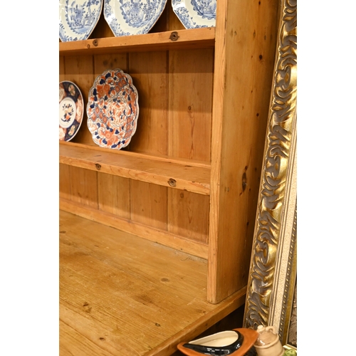 66 - A vintage waxed pine dresser with plate rack over three drawers and panelled cupboard doors, 140 cm ... 