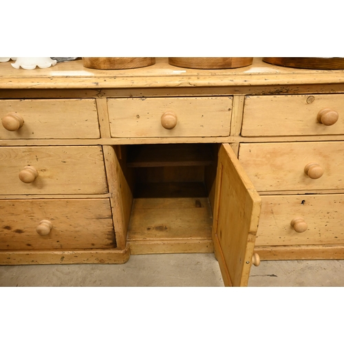 72 - A pine inverted breakfront sideboard with seven drawers surrounding the central panelled cupboard, 1... 