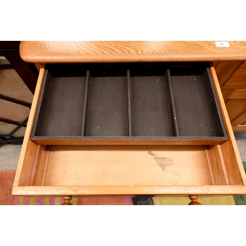 77 - A mid-century Ercol elm and beech sideboard with two drawers and panelled cupboards raised on splaye... 