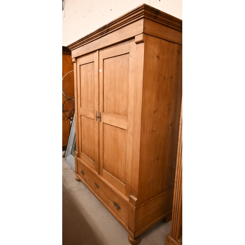 93 - A Continental pine knock-down wardrobe with twin panelled doors enclosing hanging rail on the single... 