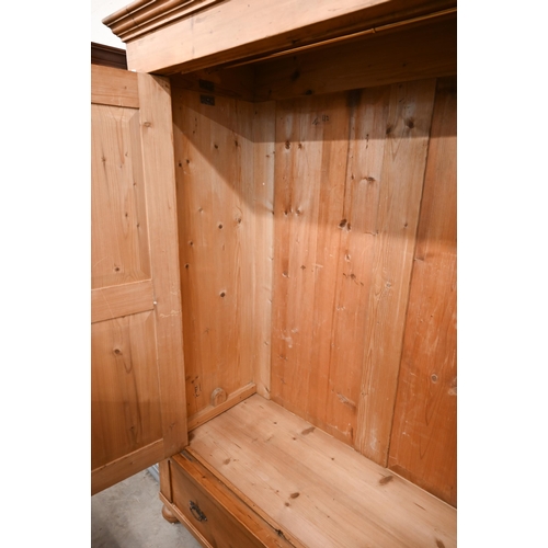 93 - A Continental pine knock-down wardrobe with twin panelled doors enclosing hanging rail on the single... 