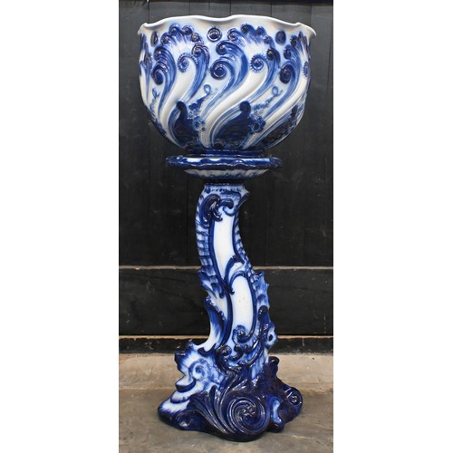 452 - An early 20th century blue and white jardiniere on stand, embossed with scrolling foliage, 85cm high