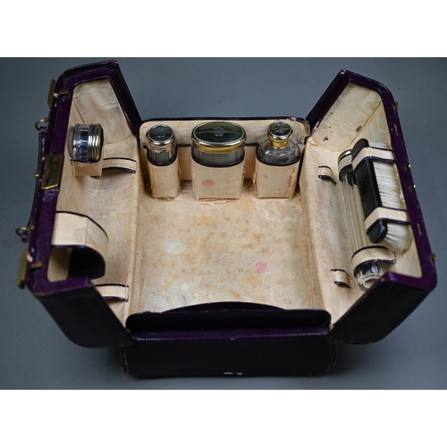 130 - An Asprey puce Morocco leather dressing case, fitted with five cut glass toilet jars - four with sil... 