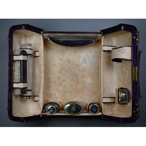 130 - An Asprey puce Morocco leather dressing case, fitted with five cut glass toilet jars - four with sil... 