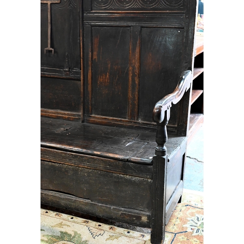 692 - A 17th century Welsh oak box settle, the crest rail with lunette carved decoration over further carv... 