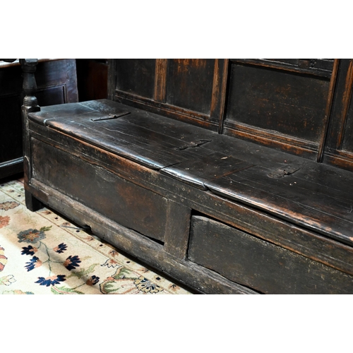 692 - A 17th century Welsh oak box settle, the crest rail with lunette carved decoration over further carv... 