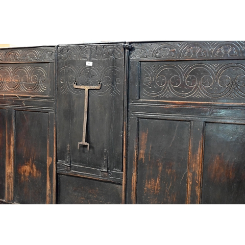 692 - A 17th century Welsh oak box settle, the crest rail with lunette carved decoration over further carv... 