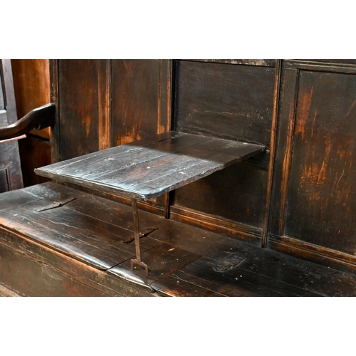 692 - A 17th century Welsh oak box settle, the crest rail with lunette carved decoration over further carv... 