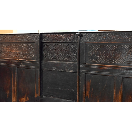 692 - A 17th century Welsh oak box settle, the crest rail with lunette carved decoration over further carv... 