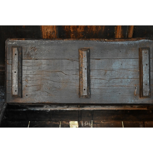 692 - A 17th century Welsh oak box settle, the crest rail with lunette carved decoration over further carv... 