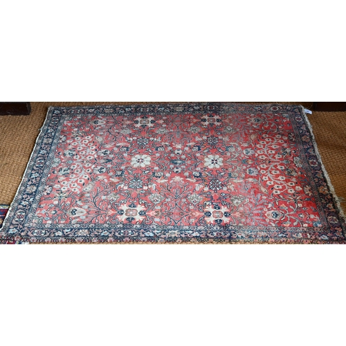 603 - An antique Persian Sarouk rug, the repeating stylised floral design on coral ground, 140 cm x 110 cm... 