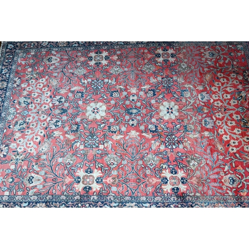 603 - An antique Persian Sarouk rug, the repeating stylised floral design on coral ground, 140 cm x 110 cm... 