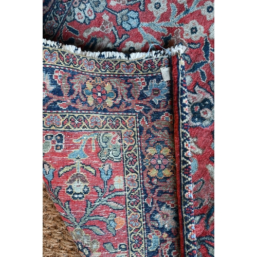 603 - An antique Persian Sarouk rug, the repeating stylised floral design on coral ground, 140 cm x 110 cm... 