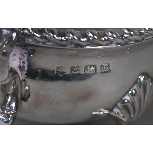 100 - A silver sauce boat in the Georgian manner, with gadrooned rim and scroll handle, on three hoof feet... 