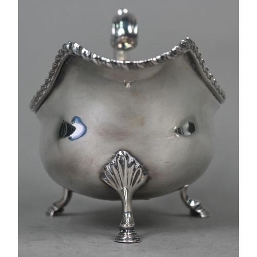 100 - A silver sauce boat in the Georgian manner, with gadrooned rim and scroll handle, on three hoof feet... 