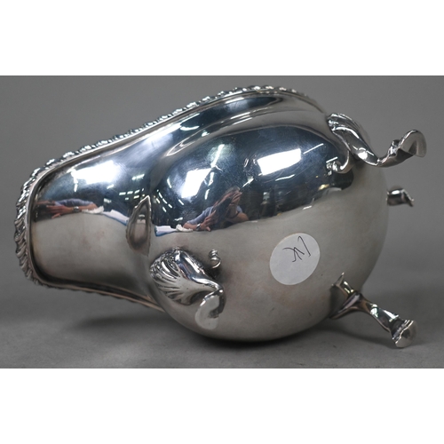 100 - A silver sauce boat in the Georgian manner, with gadrooned rim and scroll handle, on three hoof feet... 