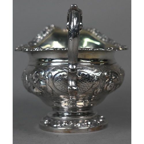 115 - A George IV silver milk jug in the Regency manner, with embossed and chased decoration and scroll ha... 