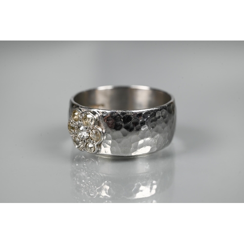 216 - A contemporary 9ct white gold wide band with hammered finish, set with seven-stone diamond cluster, ... 