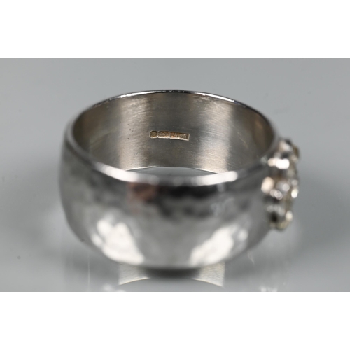 216 - A contemporary 9ct white gold wide band with hammered finish, set with seven-stone diamond cluster, ... 