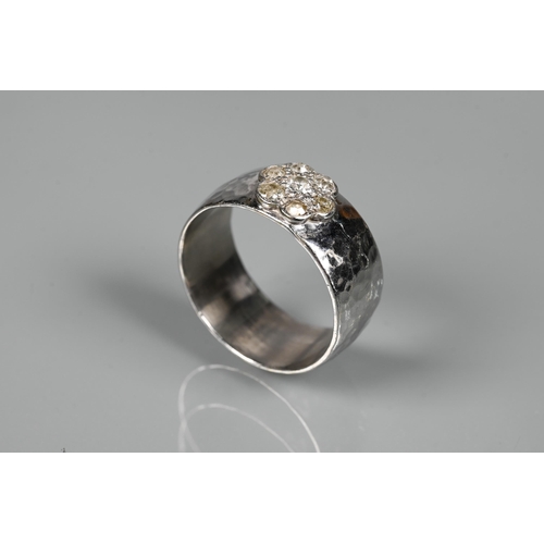 216 - A contemporary 9ct white gold wide band with hammered finish, set with seven-stone diamond cluster, ... 