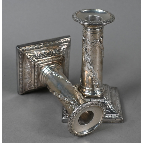 27 - A late Victorian pair of loaded silver candlesticks with embossed pillars and moulded square bases, ... 