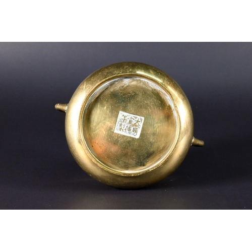 381 - A 19th century Chinese bronze small censer of compressed globular form with looped side handles stan... 