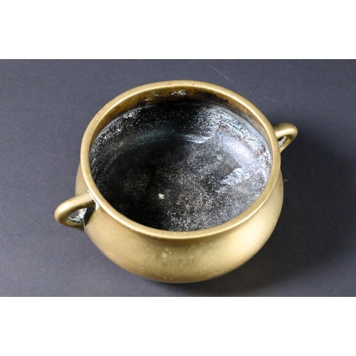 381 - A 19th century Chinese bronze small censer of compressed globular form with looped side handles stan... 